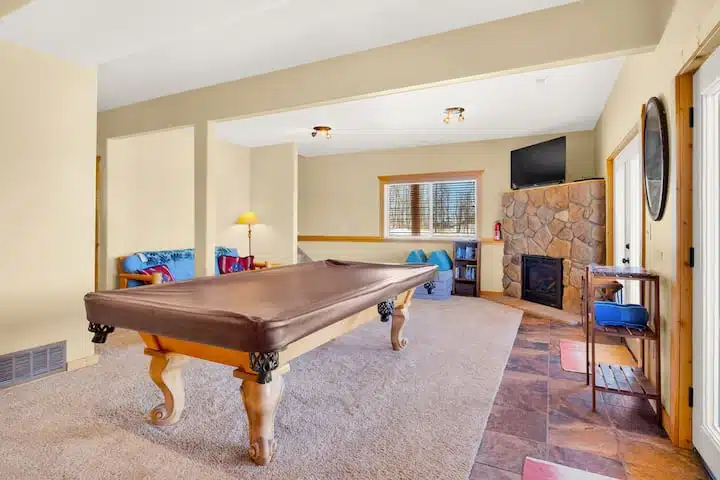 Game room equipped with pool table fireplace, tv,  and futon. You can use the patio doors to access the hot tub and don't worry, you can still see the views from the downstairs. 